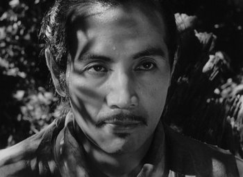 Movie still from “Rashomon” (1950), directed by Akira Kurosawa – Black and white photograph of a man's face with trees in the background; Close Up shot, High angle