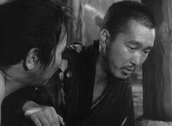 Movie still from “Rashomon” (1950), directed by Akira Kurosawa – Two men are talking to each other in a black and white photo; Close Up shot, Over the shoulder angle