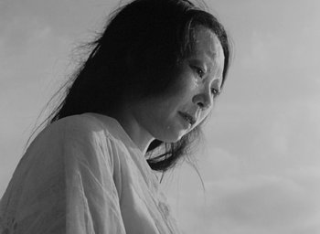 Movie still from “Rashomon” (1950), directed by Akira Kurosawa – A woman with long black hair is standing outside; Close Up shot, Low angle