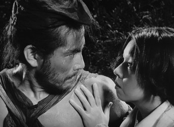 Movie still from “Rashomon” (1950), directed by Akira Kurosawa – A man and a woman holding each other in a forest; Close Up shot, Low angle
