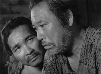 Movie still from “Rashomon” (1950), directed by Akira Kurosawa – A black - and - white photo of two men looking at each other; Close Up shot, High angle