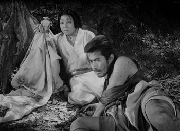 Movie still from “Rashomon” (1950), directed by Akira Kurosawa – A man and a woman sitting on the ground; Wide shot, High angle