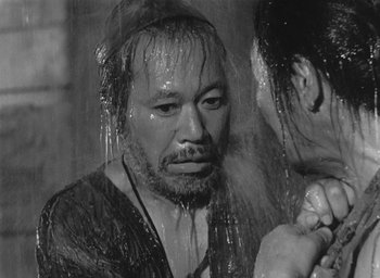 Movie still from “Rashomon” (1950), directed by Akira Kurosawa – A black and white photo of a man in the shower; Close Up shot, Over the shoulder angle