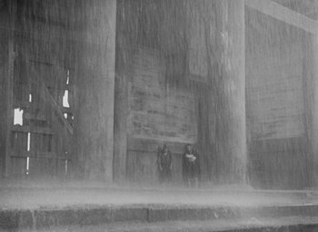 Movie still from “Rashomon” (1950), directed by Akira Kurosawa – A group of people standing in the pouring rain; Extreme Wide shot, Low angle