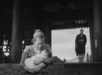 Movie still from “Rashomon” (1950), directed by Akira Kurosawa – An older woman holding a baby in her arms; Wide shot, Low angle