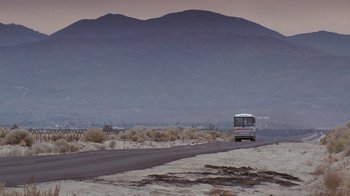Movie still from “Rat Race” (2001), directed by Jerry Zucker – A bus driving down a road near a mountain range; Extreme Wide shot, Low angle