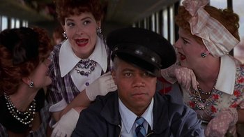 Movie still from “Rat Race” (2001), directed by Jerry Zucker – A man in a hat is surrounded by two other women; Medium shot, Over the shoulder angle
