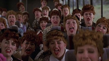 Movie still from “Rat Race” (2001), directed by Jerry Zucker – A group of people that are sitting in a room; Medium shot, High angle