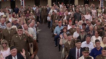 Movie still from “Rat Race” (2001), directed by Jerry Zucker – A large group of people sitting in front of a building; Wide shot, High angle