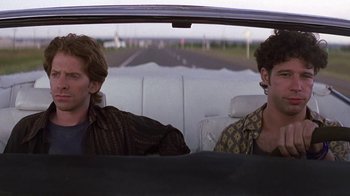 Movie still from “Rat Race” (2001), directed by Jerry Zucker – Two men sitting in the back seat of a car; Medium shot, Over the shoulder angle