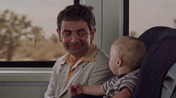 Movie still from “Rat Race” (2001), directed by Jerry Zucker – A man holding a baby in his arms and smiling; Close Up shot, Over the shoulder angle