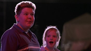 Movie still from “Rat Race” (2001), directed by Jerry Zucker – Two people standing next to each other in front of a dark background; Close Up shot, Low angle