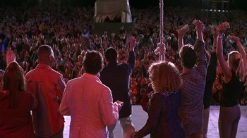 Movie still from “Rat Race” (2001), directed by Jerry Zucker – A group of people standing in front of an audience; Wide shot, High angle
