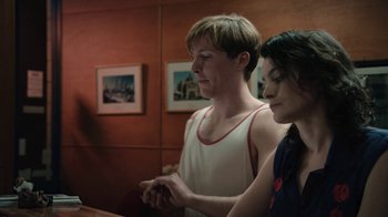 Movie still from “Glitch” (2015), created by Tony Ayres – A man and a woman looking at something on a computer screen; Medium shot, Over the shoulder angle