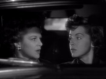 Movie still from “Raw Deal” (1948), directed by Anthony Mann – Two women are looking at one another in a car mirror; Close Up shot, Over the shoulder angle