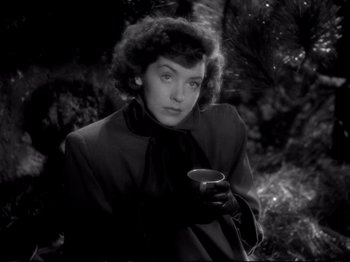 Movie still from “Raw Deal” (1948), directed by Anthony Mann – A woman holding a coffee cup while standing in a forest; Close Up shot, High angle