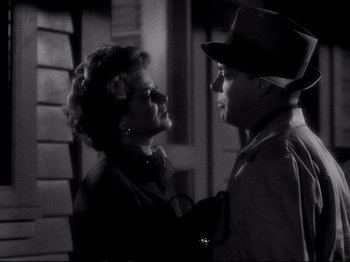 Movie still from “Raw Deal” (1948), directed by Anthony Mann – An older woman standing next to an older man; Close Up shot, High angle