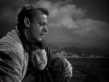 Movie still from “Raw Deal” (1948), directed by Anthony Mann – A man and a woman hugging on the beach; Close Up shot, High angle