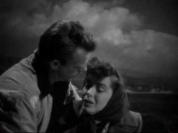 Movie still from “Raw Deal” (1948), directed by Anthony Mann – A man and a woman kissing in front of a cloudy sky; Close Up shot, High angle