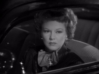 Movie still from “Raw Deal” (1948), directed by Anthony Mann – An older woman sitting in the back seat of a car; Close Up shot, Over the shoulder angle
