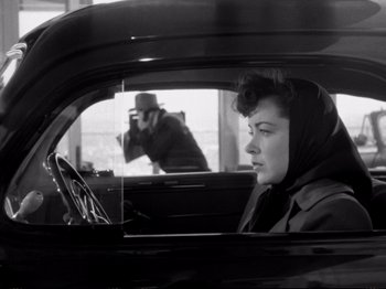 Movie still from “Raw Deal” (1948), directed by Anthony Mann – A woman sitting in the back seat of a car; Medium shot, Over the shoulder angle