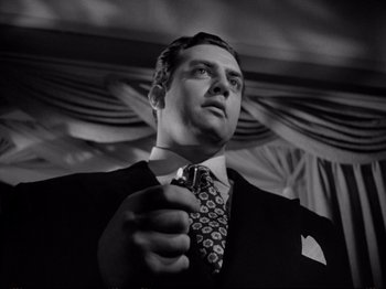 Movie still from “Raw Deal” (1948), directed by Anthony Mann – Black and white photograph of a man in a suit and tie; Close Up shot, Low angle