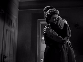 Movie still from “Raw Deal” (1948), directed by Anthony Mann – A woman hugging another woman in front of a door; Medium shot, Low angle