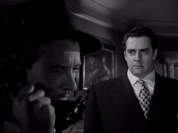 Movie still from “Raw Deal” (1948), directed by Anthony Mann – A man in a suit and tie standing next to another man in a suit and tie; Close Up shot, Low angle