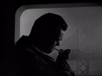 Movie still from “Raw Deal” (1948), directed by Anthony Mann – A man smoking a cigarette while looking out of a window; Close Up shot, Low angle