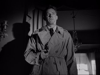 Movie still from “Raw Deal” (1948), directed by Anthony Mann – A black and white photo of a man holding a gun; Medium shot, Low angle