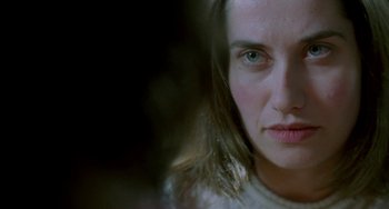 Movie still from “Read My Lips” (2001), directed by Jacques Audiard – A woman's face in a dark room; Close Up shot, Over the shoulder angle