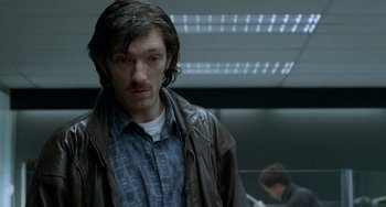Movie still from “Read My Lips” (2001), directed by Jacques Audiard – A man with long dark hair wearing a brown jacket; Close Up shot, Low angle