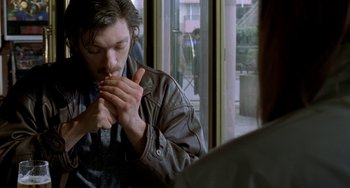 Movie still from “Read My Lips” (2001), directed by Jacques Audiard – A man sitting in front of a window eating a sandwich; Close Up shot, Over the shoulder angle