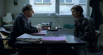 Movie still from “Read My Lips” (2001), directed by Jacques Audiard – Two people sitting at a table talking to each other; Medium shot, Over the shoulder angle