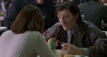Movie still from “Read My Lips” (2001), directed by Jacques Audiard – A man sitting at a table with a woman eating food; Close Up shot, Over the shoulder angle