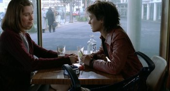 Movie still from “Read My Lips” (2001), directed by Jacques Audiard – A woman sitting at a table with a glass of water; Medium shot, High angle