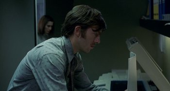 Movie still from “Read My Lips” (2001), directed by Jacques Audiard – A man in a shirt and tie looking at a computer screen; Close Up shot, Low angle