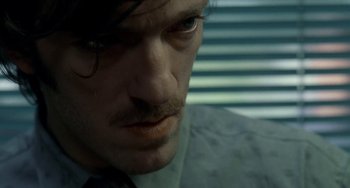 Movie still from “Read My Lips” (2001), directed by Jacques Audiard – A person wearing a suit and tie; Close Up shot, Over the shoulder angle