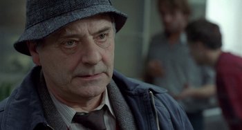 Movie still from “Read My Lips” (2001), directed by Jacques Audiard – An older man wearing a hat and a jacket; Close Up shot, Over the shoulder angle