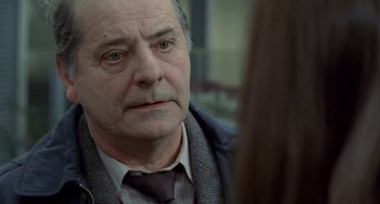 Movie still from “Read My Lips” (2001), directed by Jacques Audiard – An older man wearing a suit and a tie; Close Up shot, Over the shoulder angle