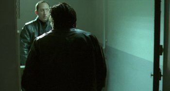 Movie still from “Read My Lips” (2001), directed by Jacques Audiard – A man standing next to another man in a room; Medium shot, Over the shoulder angle