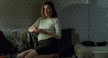 Movie still from “Read My Lips” (2001), directed by Jacques Audiard – A woman sitting on a couch in front of a wall; Medium shot, High angle