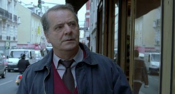 Movie still from “Read My Lips” (2001), directed by Jacques Audiard – An older man wearing a jacket and a tie; Close Up shot, Over the shoulder angle