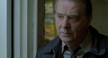 Movie still from “Read My Lips” (2001), directed by Jacques Audiard – An older man wearing a jacket and a tie; Close Up shot, Low angle
