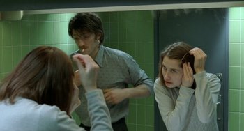 Movie still from “Read My Lips” (2001), directed by Jacques Audiard – A man and a woman in front of a bathroom mirror brushing their hair; Close Up shot, Over the shoulder angle
