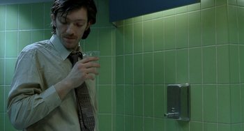 Movie still from “Read My Lips” (2001), directed by Jacques Audiard – A man holding a glass of water in a bathroom; Medium shot, Low angle