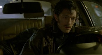 Movie still from “Read My Lips” (2001), directed by Jacques Audiard – A man sitting in the back seat of a car; Close Up shot, Low angle