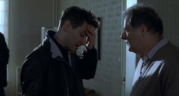Movie still from “Read My Lips” (2001), directed by Jacques Audiard – A man with his hand on his head and another man with his hand on his forehead; Close Up shot, Over the shoulder angle