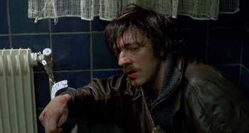 Movie still from “Read My Lips” (2001), directed by Jacques Audiard – A man in a brown jacket looking at his watch; Close Up shot, High angle