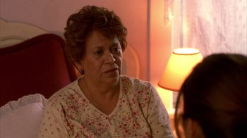 Movie still from “Real Women Have Curves” (2002), directed by Patricia Cardoso – An older woman sitting in front of a lamp in a living room; Close Up shot, Over the shoulder angle